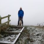 Dog and handler out for a walk in the snow at Oswestry Hill Fort